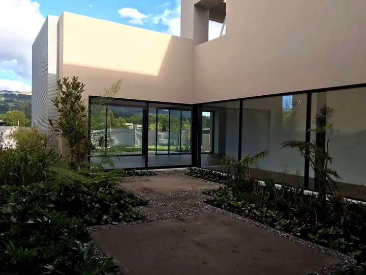 Patio interior con ventanales de piso a techo en vivienda Steel Framing